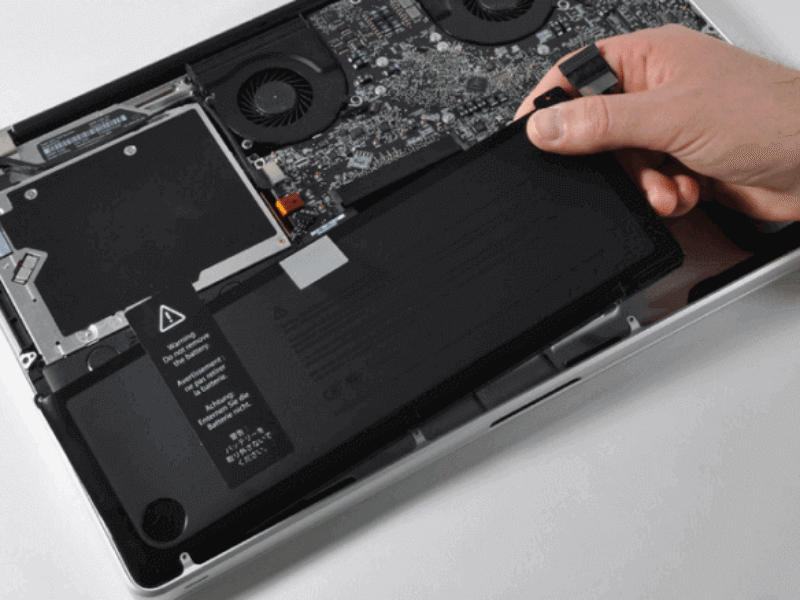 Technician performing MacBook Pro battery replacement in a repair center.