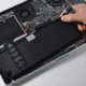 Technician performing MacBook Pro battery replacement in a repair center.
