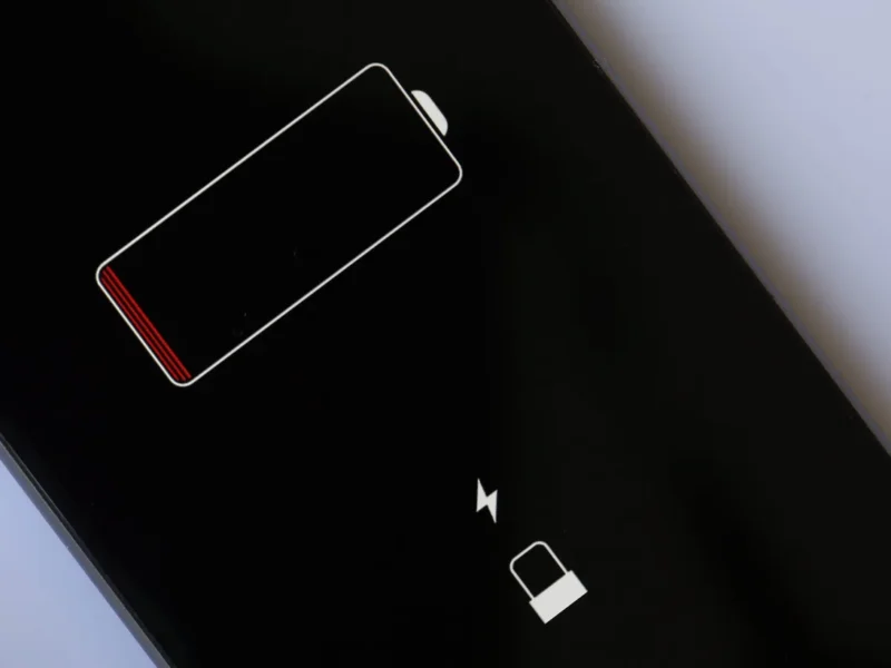 Technician checking iPhone battery draining fast causes and applying fixes.